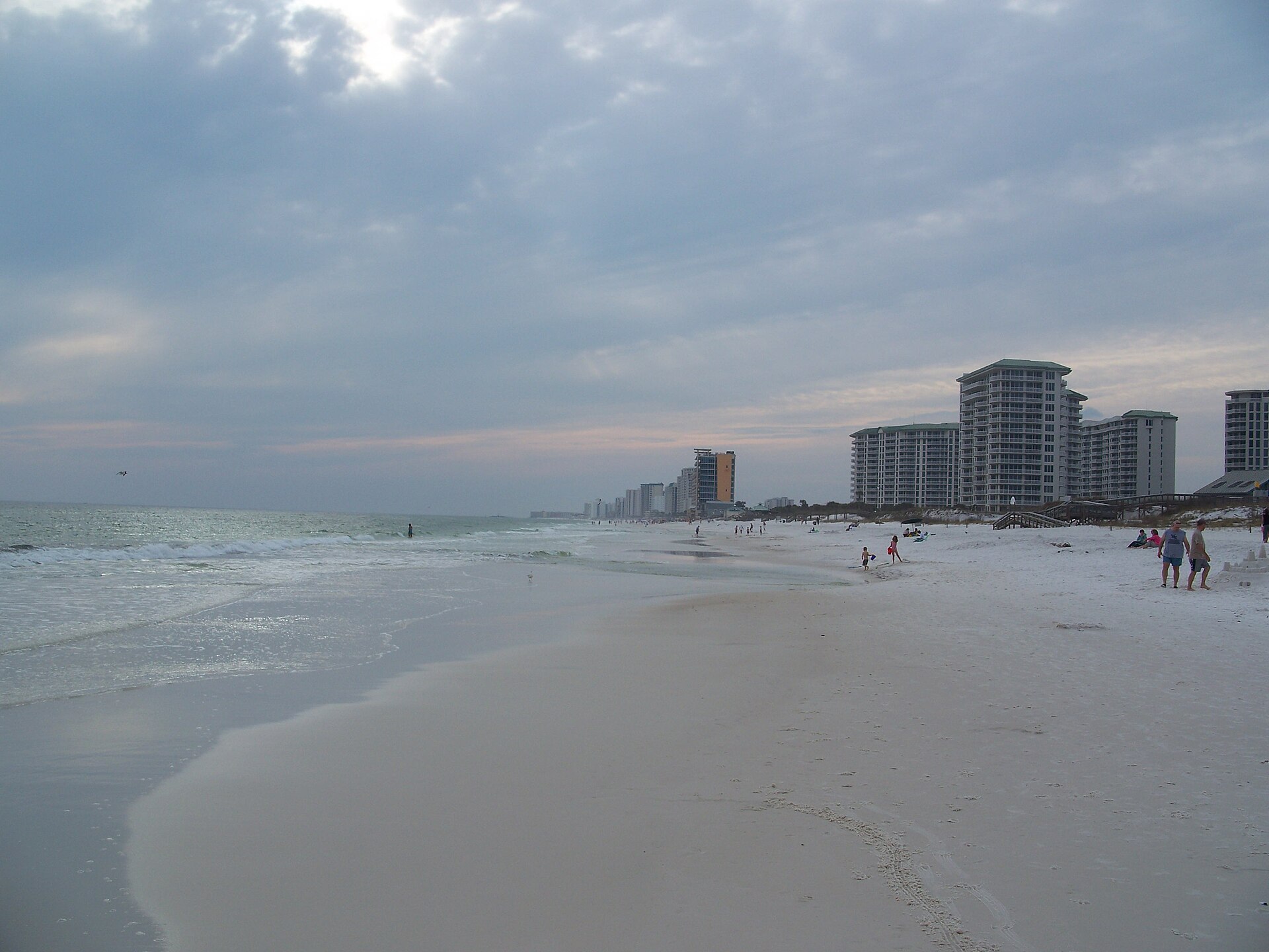 Wide Destin beach at sunset with Gulf-front condo towers along the shoreline